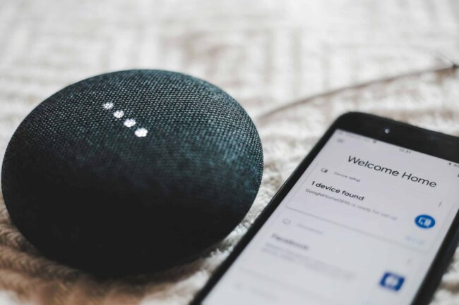 Smart-Tips-for-Building-a-Smart-Home-on-a-Budget-scaled.jpg turned-on charcoal Google Home Mini and smartphone